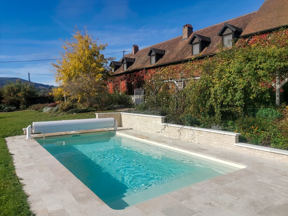 Big Rectangular Swimming Pool with Pavement in large White Tiles and Surrounded by Trees and Bushes