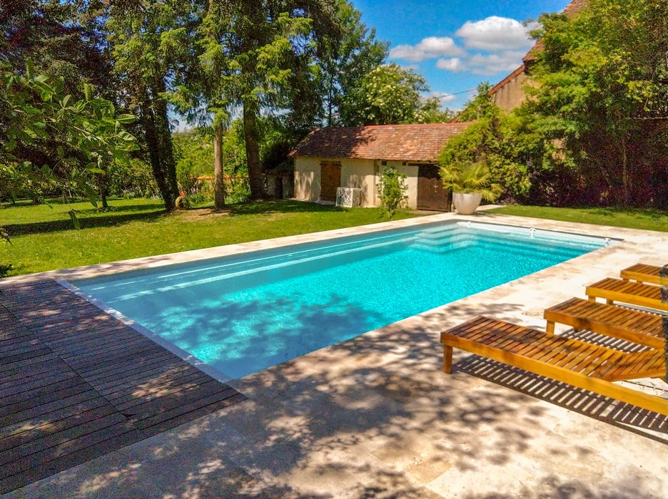 Piscine extérieure avec jets d'hydromassage en fonctionnement, entourée d'un deck en bois naturel
