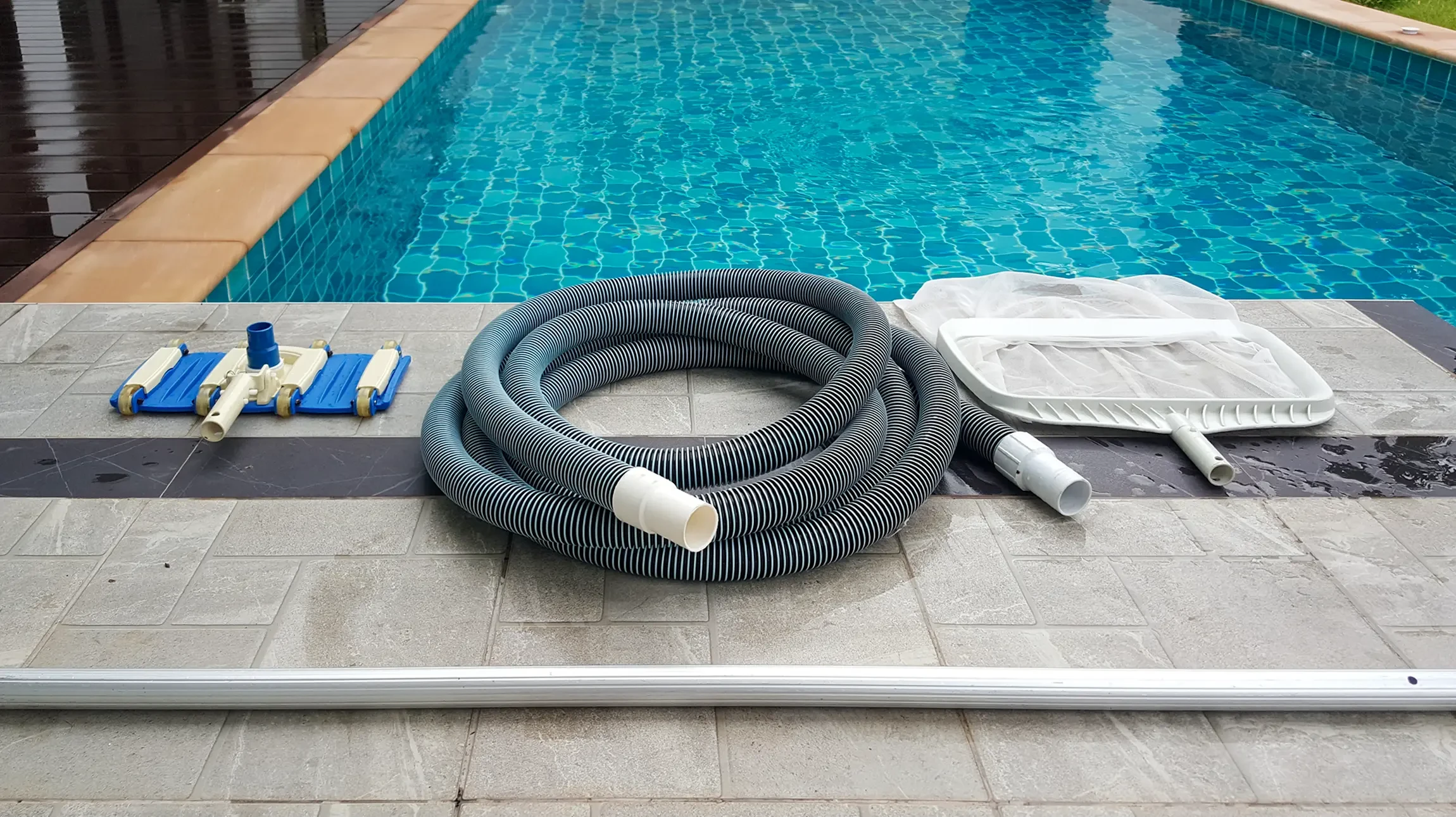 Robot nettoyeur automatique de piscine en fonctionnement dans bassin r&eacute;sidentiel avec margelles en b&eacute;ton teint&eacute; orange